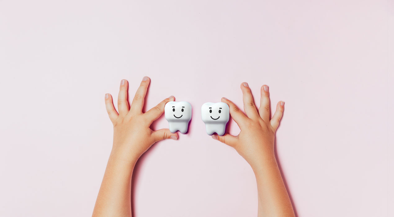 Kinder Zahnheilkunde bedeutet Schutz der Zähne von Anfang an.. Kleine Hände halten 2 Zähne.